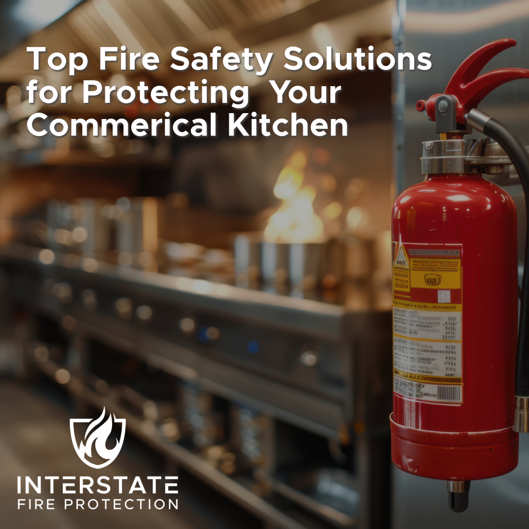 A commercial kitchen with a red fire extinguisher in the foreground, and a stovetop in the background with flames, illustrating the importance of fire safety. The title reads, "Top Fire Safety Solutions for Protecting Your Commercial Kitchen," with the Interstate Fire Protection logo in the bottom left corner.